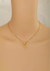 Close-up of a gold cross pendant necklace with clear cubic zirconia on a mannequin
