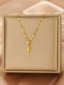 Macro shot of gold cross pendant with micro zircon inlay on shiny sequin chain in a gift box
