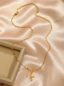 Detail of gold cross pendant with lobster clasp and S.STEEL stamp on champagne silk