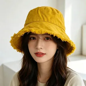 Close-up of bright yellow cotton bucket hat featuring trendy frayed edge brim details