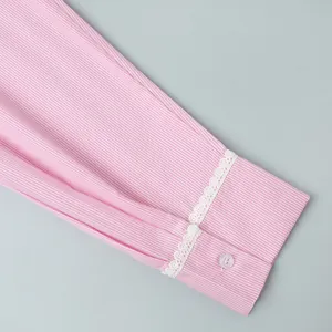 Detailed close-up of pink striped shirt cuff with delicate white lace trim and pink button