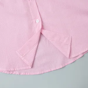 Detailed close-up of pink striped shirt hem with fine stitching and white resin button