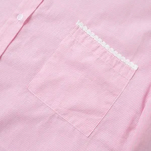 Detail of pink striped fabric with lace-trimmed chest pocket and white button