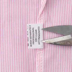 Macro shot of the care label and washing instructions on pink striped fabric