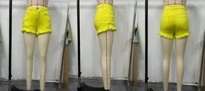 Detailed view of yellow denim shorts featuring frayed hems and distressed ripped textures