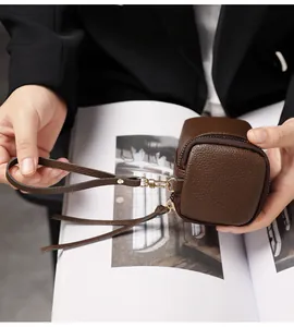 Close-up of vintage brown pebble leather mini bag with gold hardware held by a person