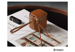 Detail of tan vintage leather mini makeup pouch with golden zipper on a fashion magazine