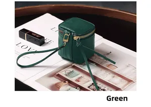 Detail of green lychee leather mini pouch with gold zipper and strap on a magazine