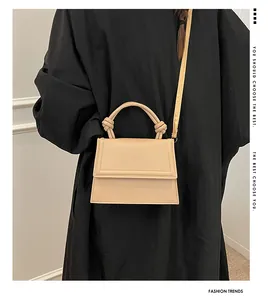 Detail shot of a beige PU leather crossbody bag with a knot handle and shoulder strap