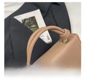 Detail of minimalist khaki crossbody bag featuring a unique twisted top handle design