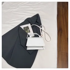 Detail shot of a minimalist white trapezoid handbag with sleek leather texture