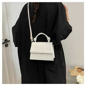 Rear view of model wearing a white mini crossbody bag with a decorative knotted handle