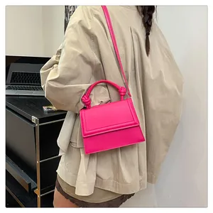 Detail of rose pink mini crossbody bag featuring a unique knotted handle design and flap closure