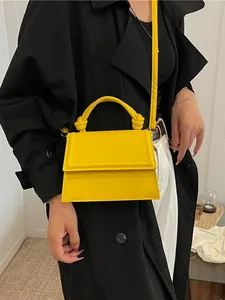 Minimalist bright yellow trapezoidal crossbody bag with knotted handle and slim strap
