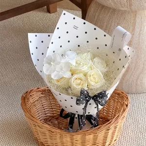 Detail of white rose bouquet with black polka dot wrapping paper and ribbon decoration
