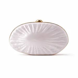 Detailed close-up of shell-textured acrylic clutch bag with golden metal frame and clasp