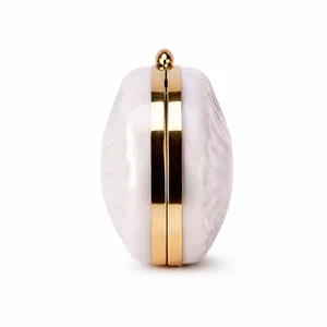 Macro detail of white marble acrylic evening clutch with gold metal frame and spherical clasp