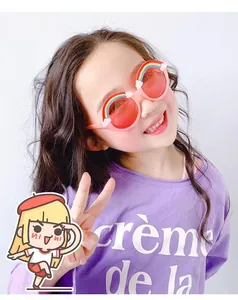 Close-up of pink round children sunglasses with rainbow and cloud decorative details