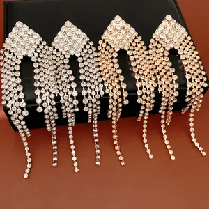 Macro view of elegant rhinestone diamond-shaped tassel earrings in gold and silver finishes