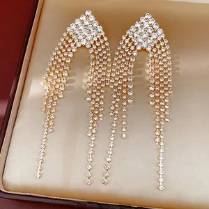 Elegant gold-toned rhinestone tassel earrings displayed inside a luxury champagne jewelry box
