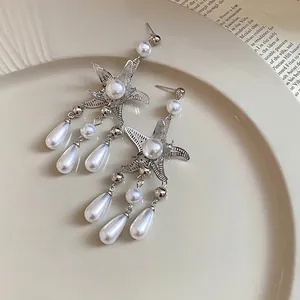 Silver starfish earrings with white pearl drop tassels on a vintage plate