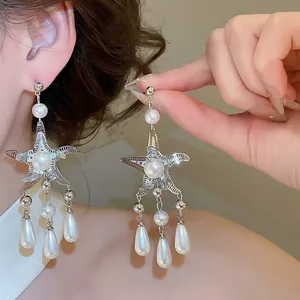 Detailed macro shot of silver starfish drop earrings with white pearls and tassels