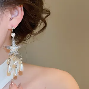 Close-up detail view of elegant silver starfish drop earrings featuring pearl tassels