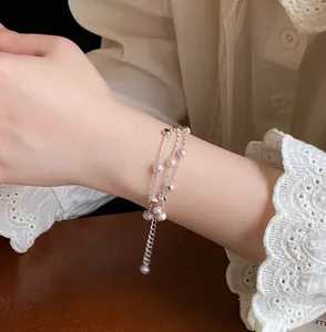 Eleganter mehrlagiger Perlenarmreif mit Silberketten und Herzanhängern am Handgelenk