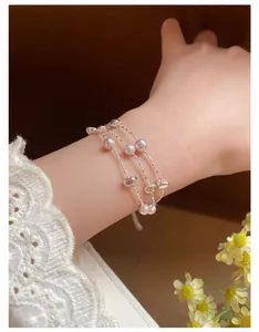 Detailansicht eines eleganten mehrlagigen Perlenarmbands mit Silberperlen am Handgelenk.