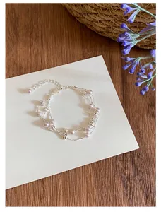 Detailansicht eines mehrlagigen silbernen Armbands mit lila Perlen auf weißer Karte.