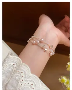 Detailansicht eines eleganten mehrlagigen rosa Perlenarmbands mit Silberperlen am Handgelenk