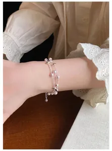 Nahaufnahme eines filigranen mehrlagigen Perlenarmbands mit Silberperlen am Handgelenk