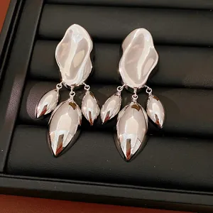 Primo piano di orecchini geometrici irregolari in argento lucido