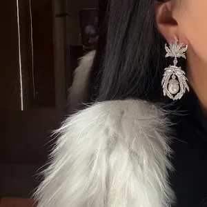 Détail de boucles d'oreilles élégantes en zircon avec perle portées par un mannequin