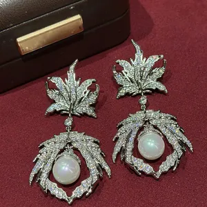 Gros plan sur d'élégantes boucles d'oreilles en forme de feuille avec zircons et perles