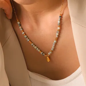 Primo piano dettagliato di una collana di pietre naturali con ciondolo a goccia d'oro.