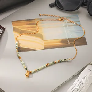 Primo piano di collana in pietra naturale con ciondolo a goccia dorato lucido