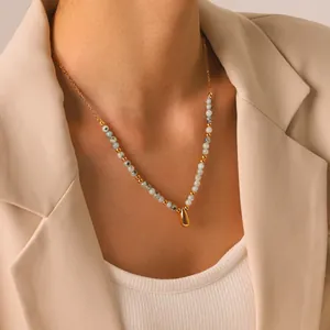 Primo piano di una collana in pietra naturale con ciondolo a goccia d'oro sul modello