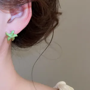 Primer plano de un pendiente de estrella de mar verde con bordes dorados en una modelo