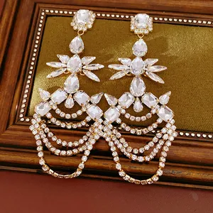 Detail view of luxurious gold-tone earrings with clear teardrop crystals and tassels.