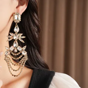 Close-up of elegant gold tassel earrings with shimmering geometric rhinestone accents.