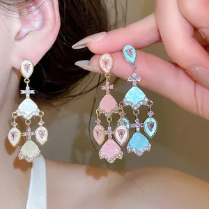 Gros plan détaillé de boucles d'oreilles chandelier en émail avec des accents de zircon rose