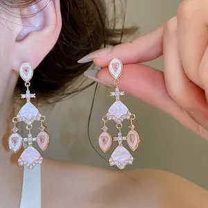 Vue détaillée de boucles d'oreilles chandelier plaquées or avec zircons roses.