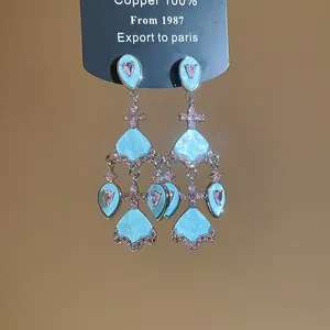Détail des boucles d'oreilles lustre en éventail bleu clair avec des accents de zircone rose.