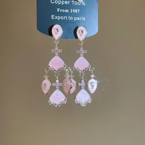 Vue détaillée des boucles d'oreilles pendantes roses en forme d'éventail, dorées 18 carats et zircon