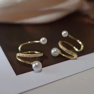 Vista dettagliata di eleganti clip per orecchie a spirale dorate con zirconi e perle bianche