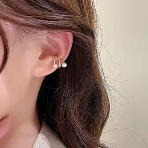Dettaglio di un elegante ear cuff dorato con perle bianche e zirconi cubici incastonati