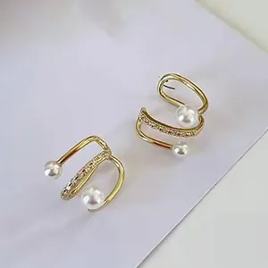 Vista dettagliata di ear cuff dorati con zirconi scintillanti e perle eleganti.