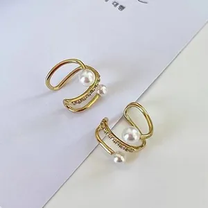 Vista dettagliata di eleganti ear cuff in perle dorate con accenti in zirconi scintillanti.