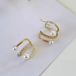 Primo piano dettagliato di ear cuff dorati con perle e zirconi brillanti e luminosi
